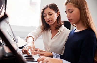 piano teacher and student sitting
            at a piano