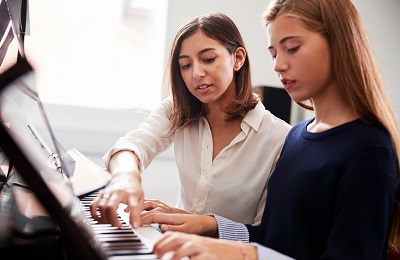 piano teacher and student sitting
            at a piano